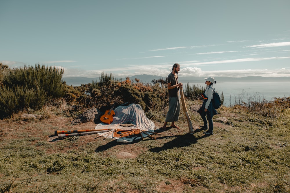 a couple of people standing on top of a grass covered field