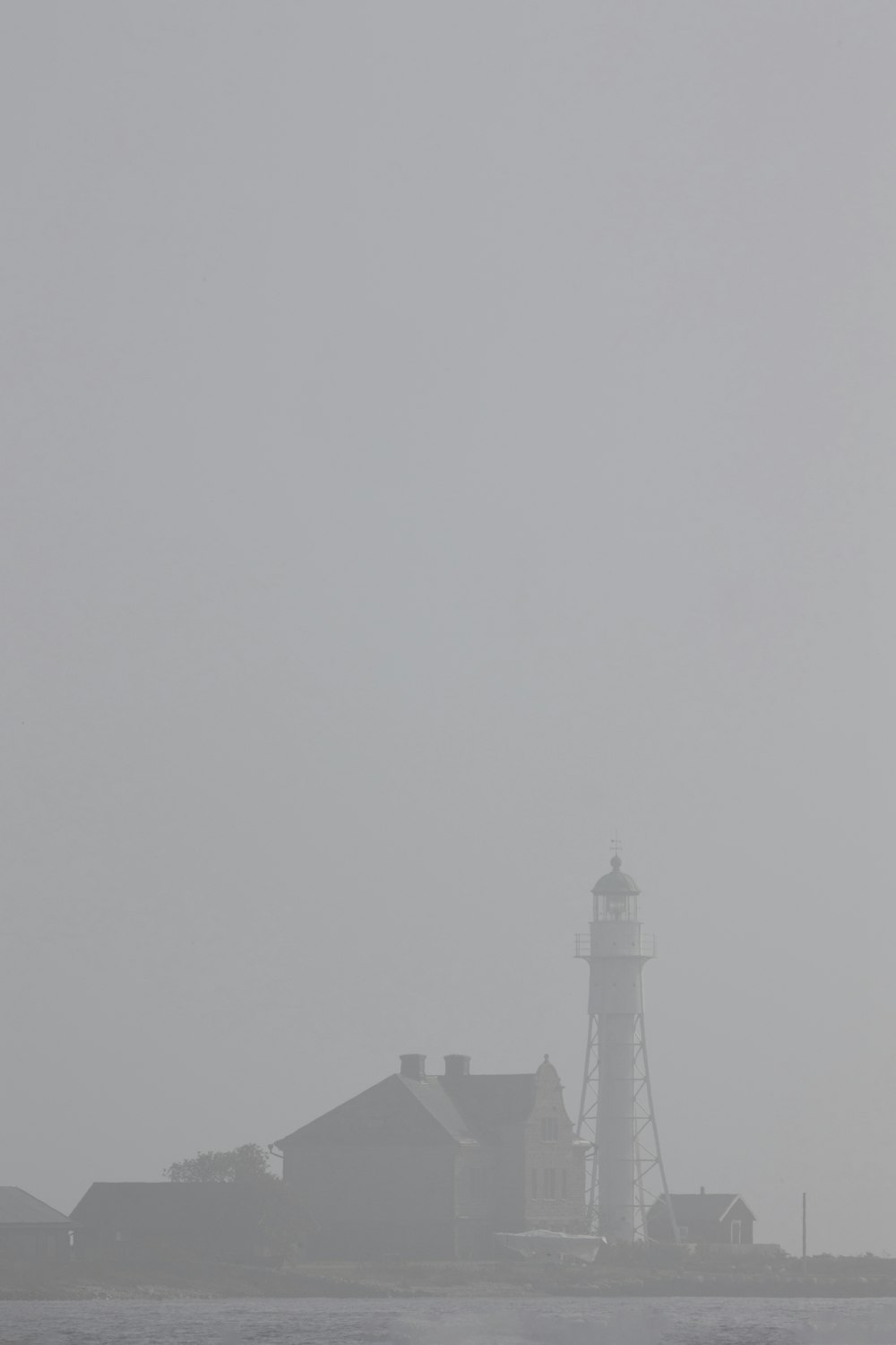 a lighthouse on a foggy day with a lighthouse in the background