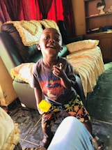 Smiling child wearing colorful clothes in a bright room.