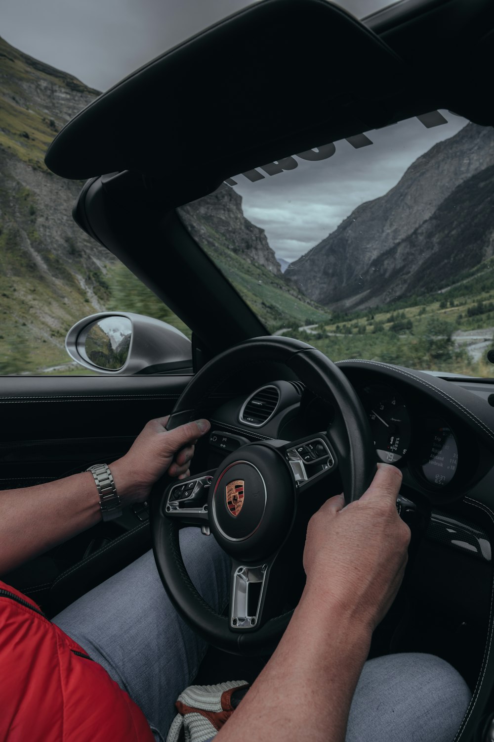 a man driving a car with mountains in the background