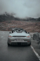 Porsche Macan cruising along a desert highway with mountains in the distance.