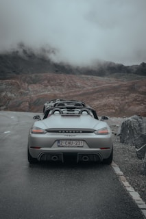 A sleek, bright red Porsche 911 parked on a winding mountain road during golden hour, hinting at adventure ahead.