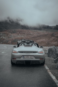 A sleek, bright red Porsche 911 parked on a winding mountain road during golden hour, hinting at adventure ahead.