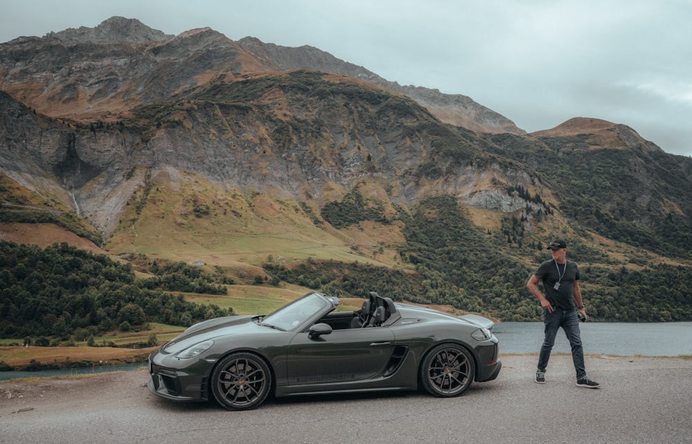 a man standing next to a gray sports car