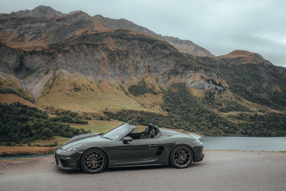 a grey sports car parked in front of a mountain