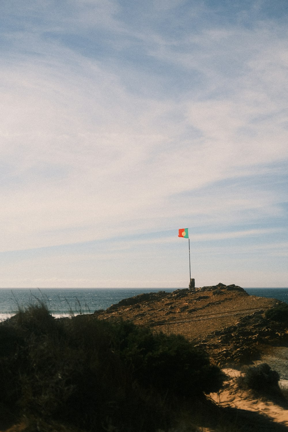 a flag on top of a hill near the ocean