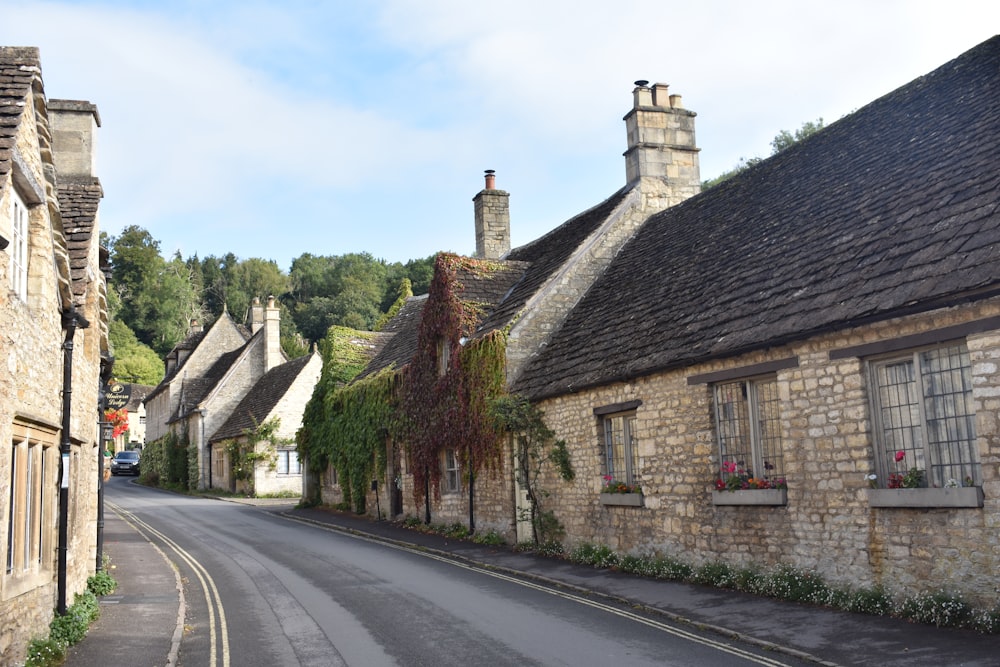 a street lined with stone buildings next to a lush green forest