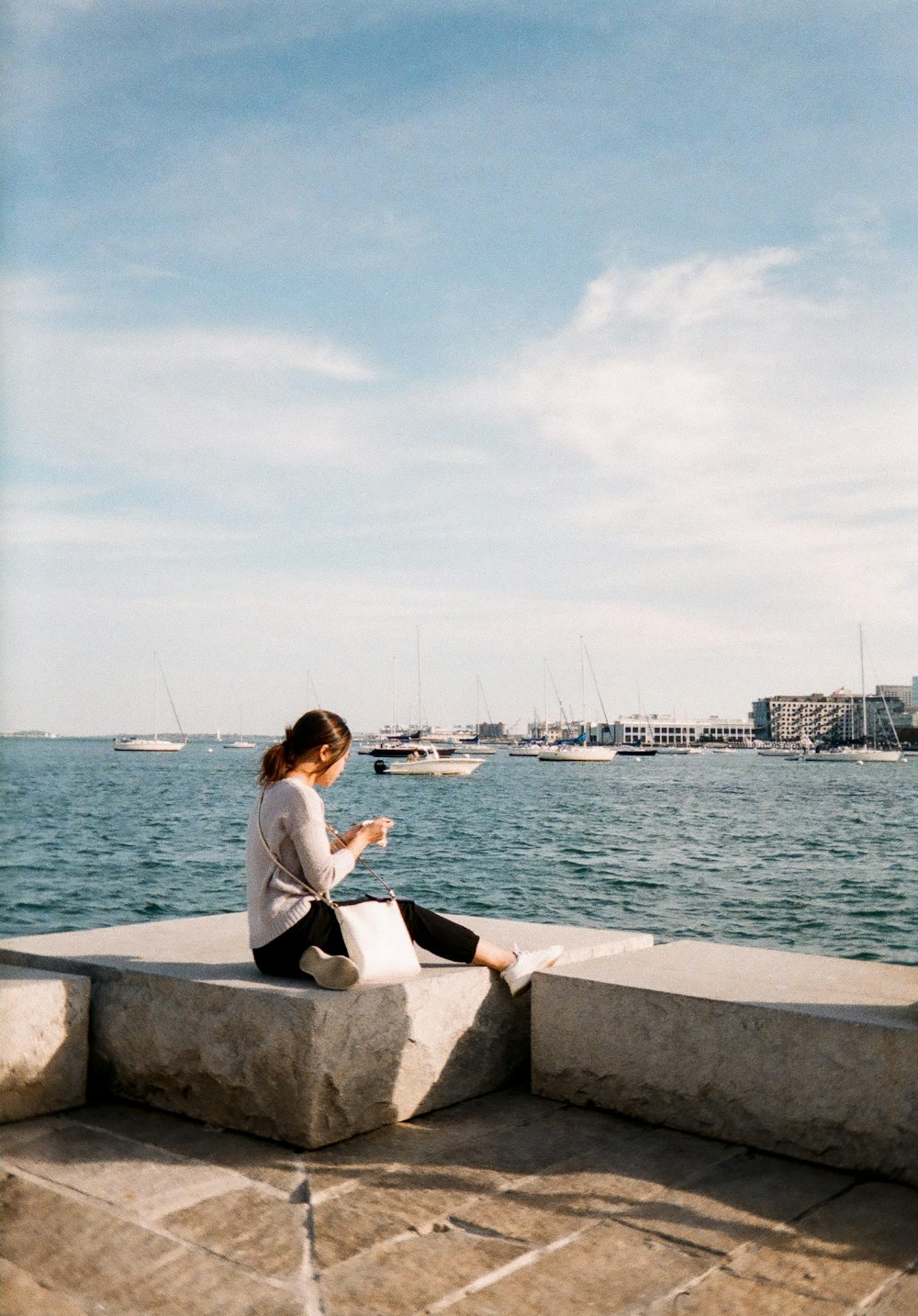 a woman sitting on a ledge looking at her cell phone