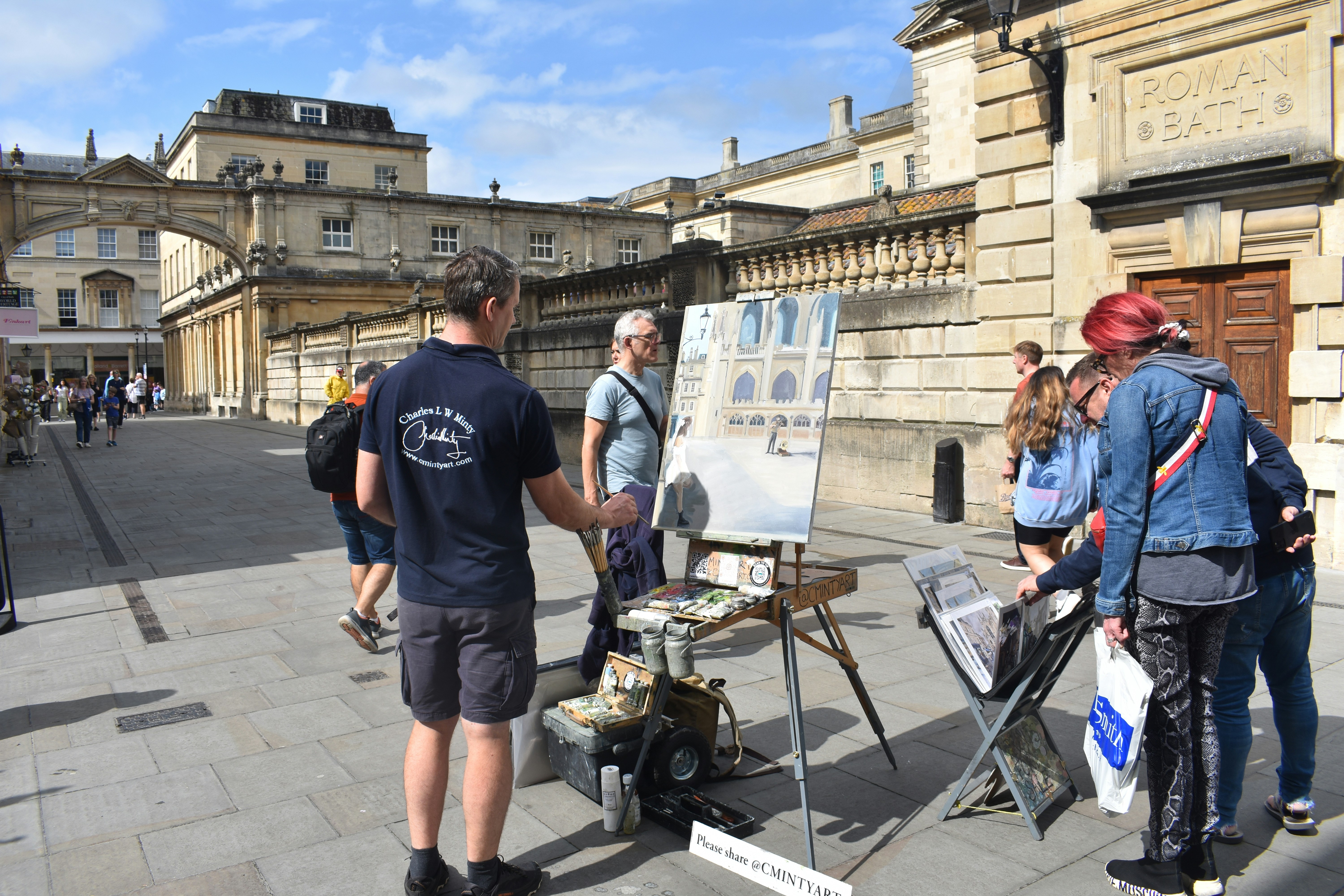 a group of people standing around a painting on a easel