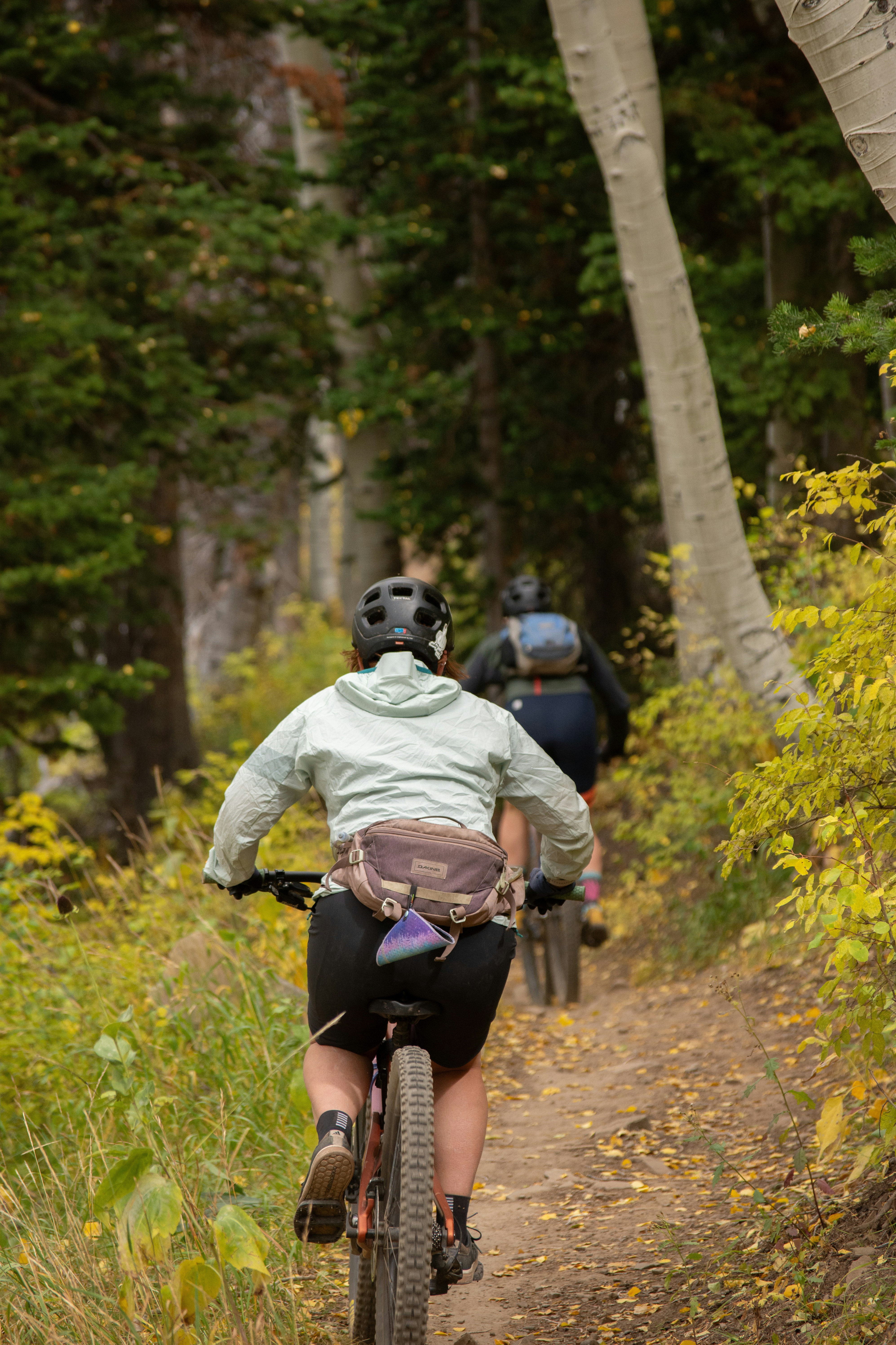 a couple of people riding bikes down a dirt road