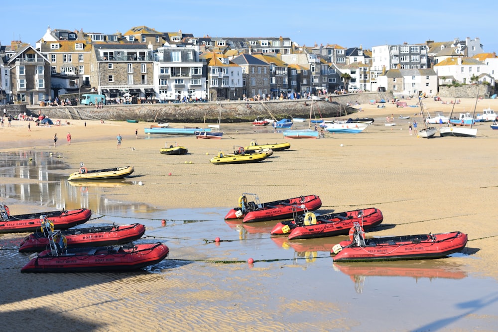 a group of red boats sitting on top of a sandy beach