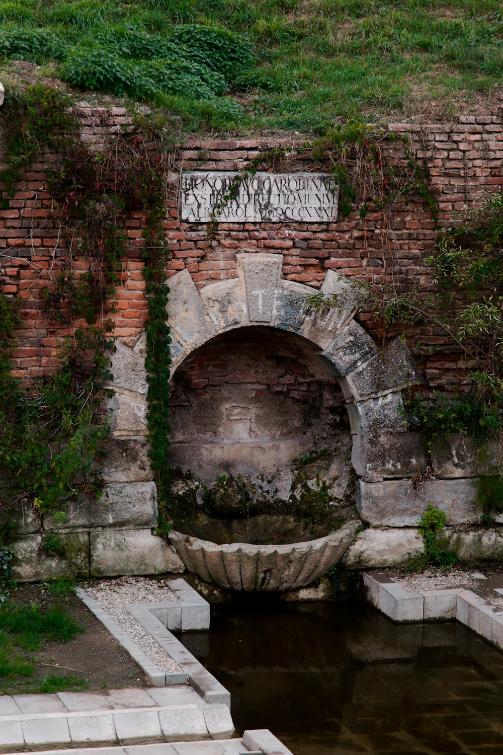 una pared de ladrillo con una fuente de agua en ella