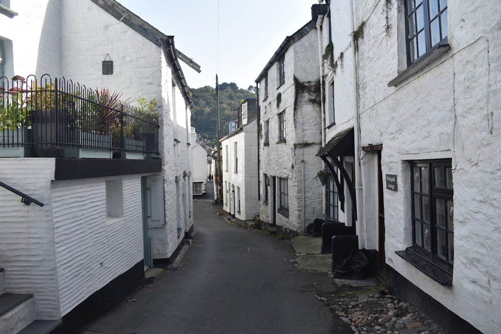 a narrow street with white buildings and a balcony