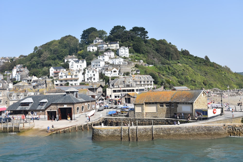 a group of buildings sitting on top of a hill next to a body of water