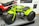 A bright green three-wheeled all-terrain vehicle with large, thick tires is prominently displayed next to a red and black CB125T motorcycle. The green vehicle features a compact engine and is stationed on a platform, surrounded by informational panels discussing motorcycle history.
