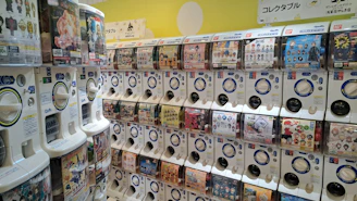 A close-up of a colorful capsule toy dispenser installed in a bright supermarket aisle.