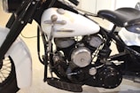 A close-up view of the engine and body of a vintage Harley-Davidson motorcycle, showcasing its intricate mechanical components and parts, including the cylinders, exhaust, and branding on the white tank.