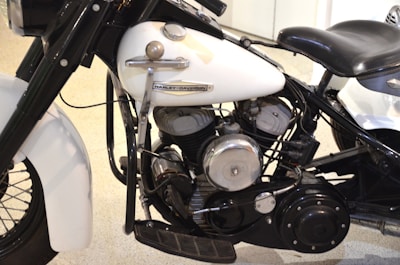 A close-up view of the engine and body of a vintage Harley-Davidson motorcycle, showcasing its intricate mechanical components and parts, including the cylinders, exhaust, and branding on the white tank.