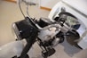 The image features a close-up of a classic motorcycle with a black and white color scheme. The front view highlights the handlebars, headlight, and part of the engine. A sidecar is attached to the motorcycle, with a black seat and a chrome rearview mirror visible.