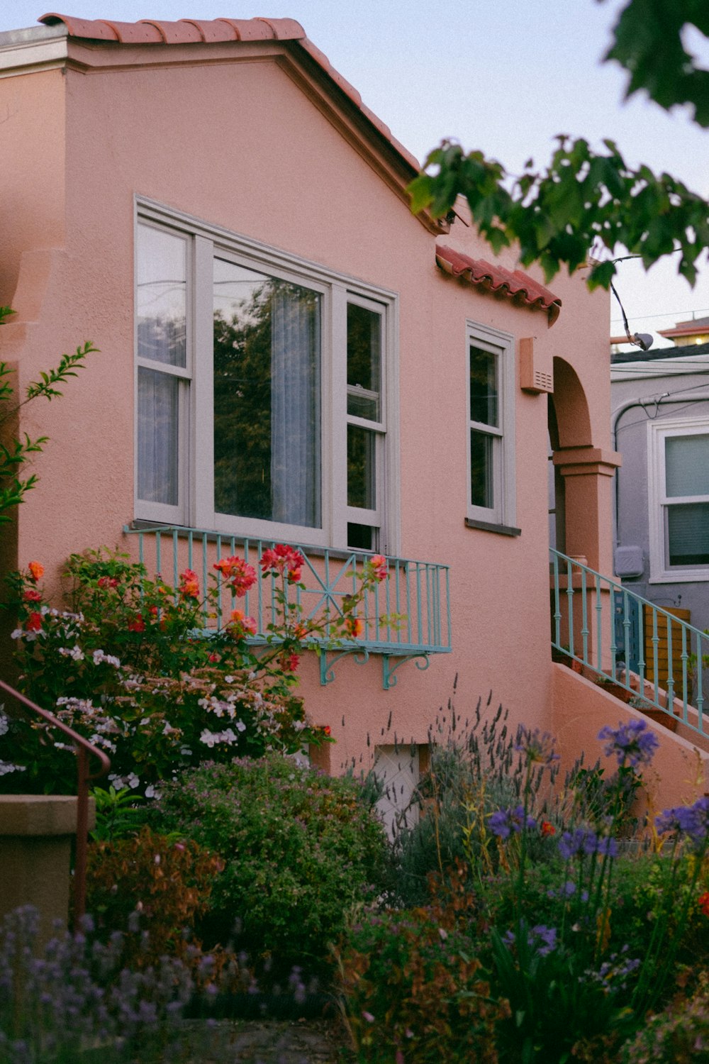 a pink house with a balcony and flower garden