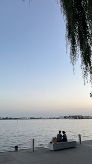 Couple enjoying live music on benches by the waterfront in the evening