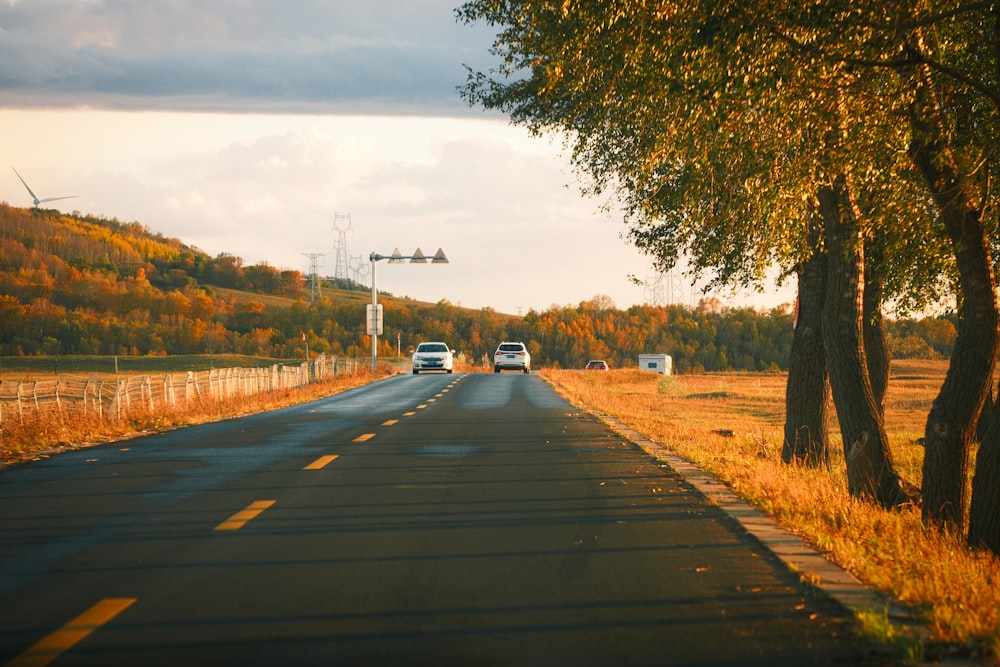 two cars are driving down a rural road