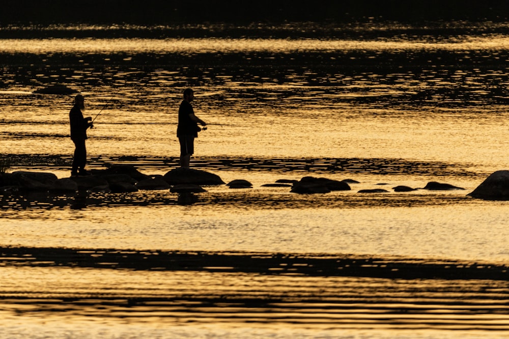 a couple of people standing on top of a body of water