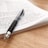 A close-up of an open notebook with handwritten notes and a pen resting on a wooden desk.