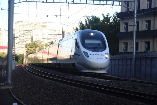 Aerial shot of the bullet train gliding along a curved track through a vibrant cityscape.