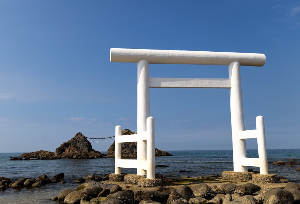 a large white sculpture sitting on top of a rocky beach