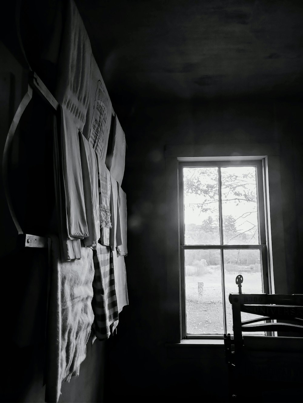 uma foto em preto e branco de uma janela em um quarto escuro