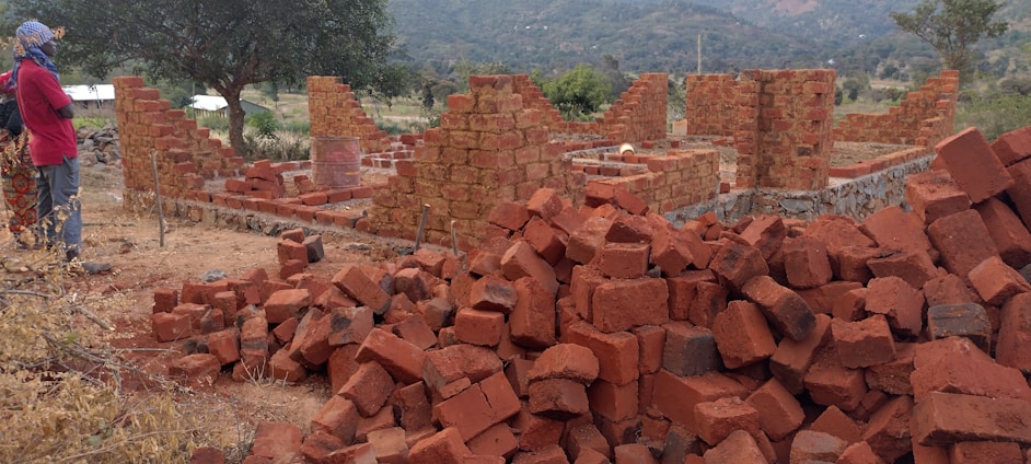 Photo of Bruno Borges inspecting a brick wall construction site on a sunny day.