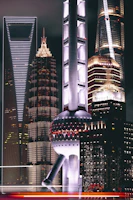 Nighttime cityscape featuring illuminated luxury buildings with reflective glass surfaces.