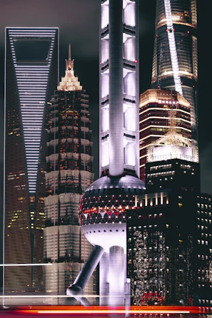Nighttime cityscape featuring illuminated luxury buildings with reflective glass surfaces.