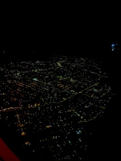 A nighttime cityscape showing a grid of illuminated buildings and streets.