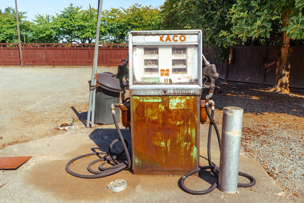 an old rusty gas pump sitting on the side of a road