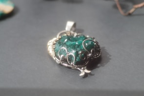 Silver pendant necklace glowing softly under natural light with healing crystal accents.