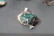 Close-up of a delicate silver pendant with a vibrant natural gemstone glowing softly in warm light.