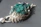 Elegant emerald pendant displayed against a charcoal grey background with subtle golden accents