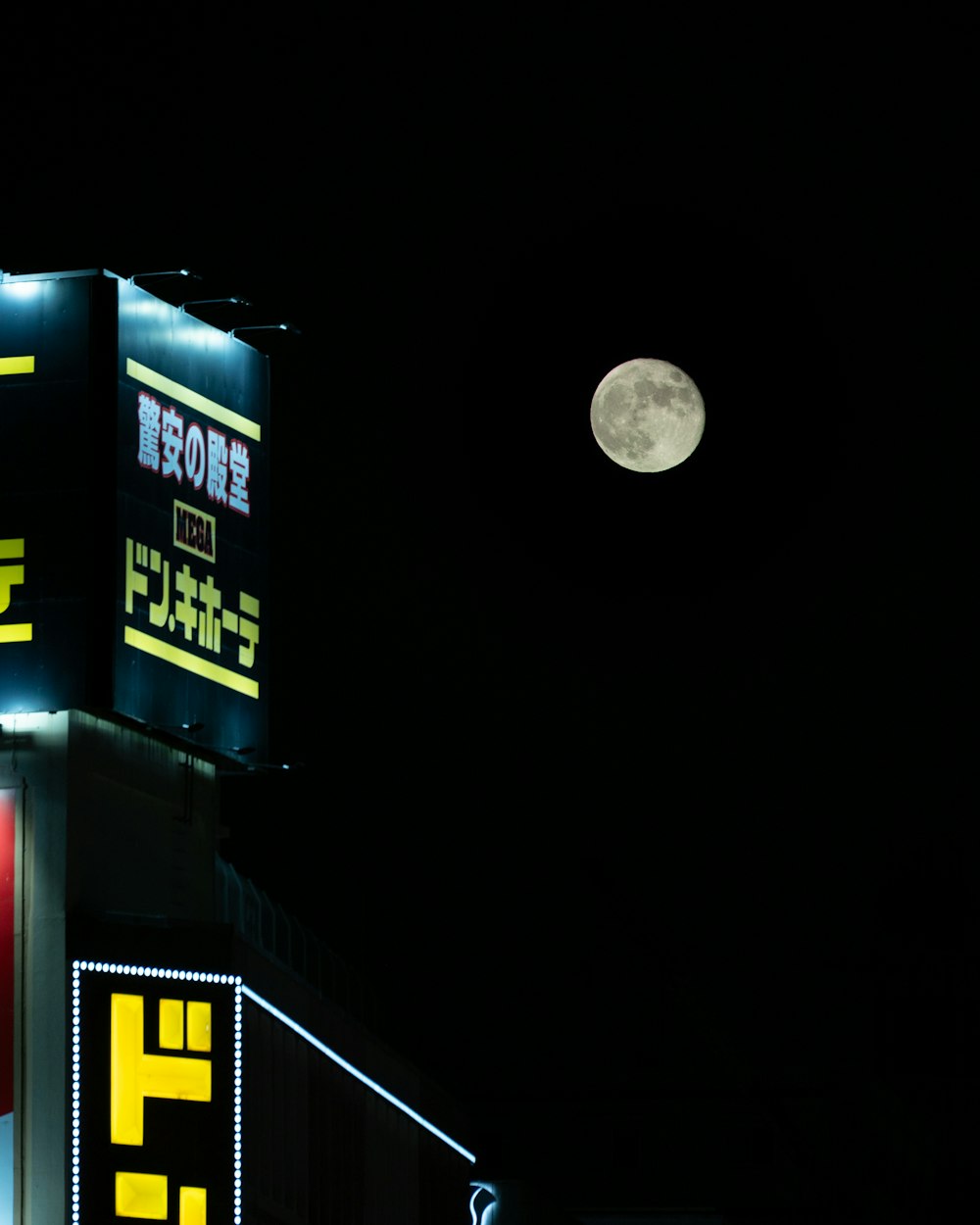 Une pleine lune est dans le ciel au-dessus d’un bâtiment