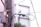 A utility pole is depicted with multiple black wires and cables attached. A grey electrical junction box is mounted on the pole. The background appears to be an out-of-focus building with a light, soft color palette. The setting seems urban and the focus is on the interconnected network of cables.