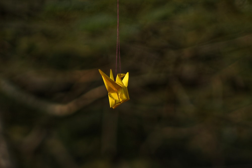 a yellow origami bird hanging from a string