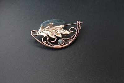 Vintage-inspired brooch with detailed metalwork showcased on a dark velvet cloth.