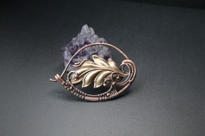 Elegant copper necklace featuring a raw amethyst pendant glowing softly against a linen background.