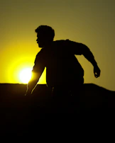 Silhouette of a woman in motion against a sunset, the terracotta accents glowing warmly.