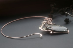 An elegant necklace combining brass pocket watch parts with polished green stones, softly lit to highlight textures