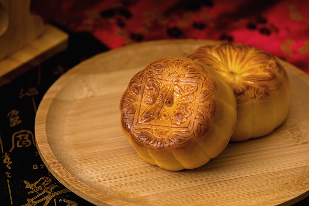 two chinese buns sitting on a wooden plate