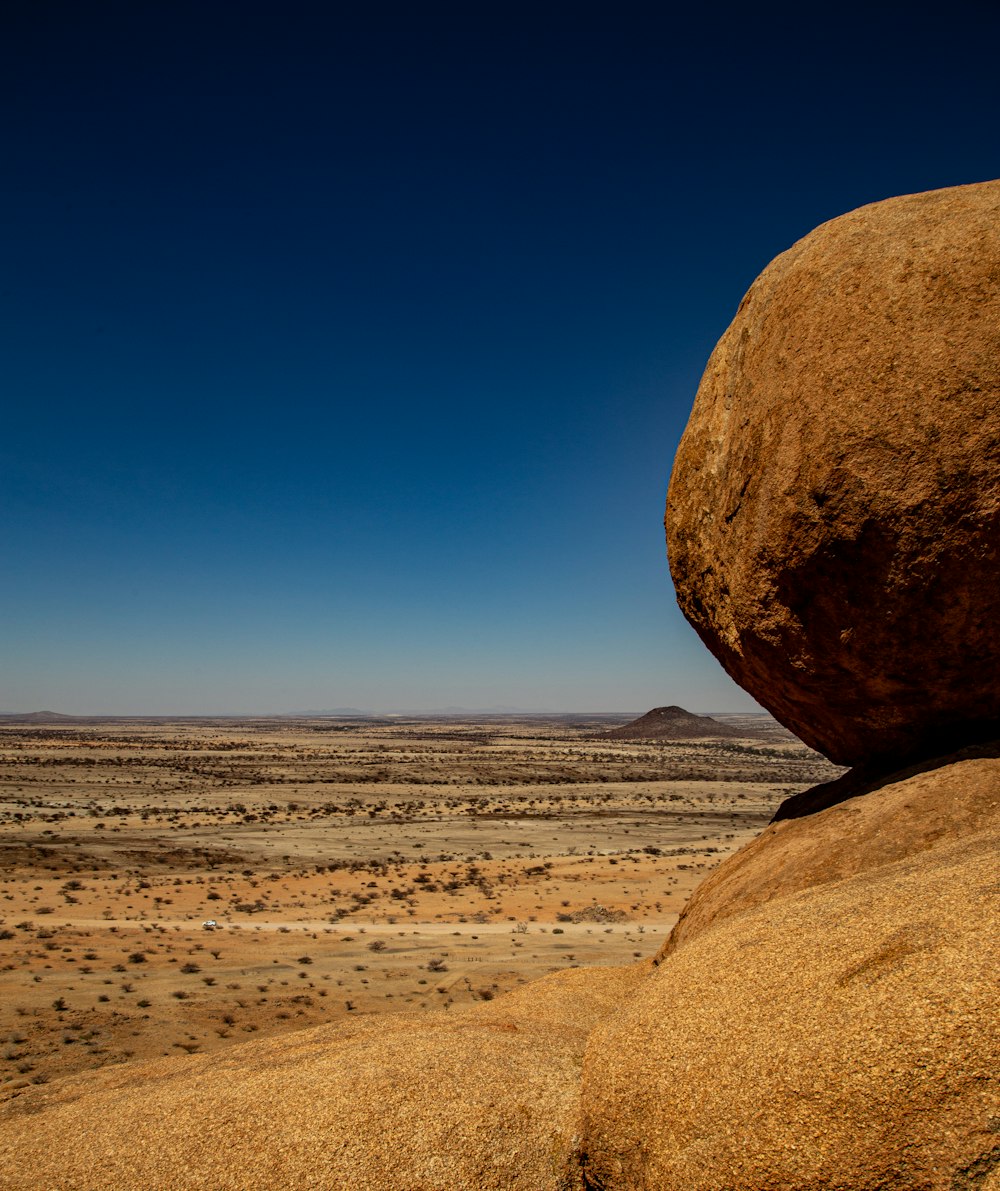 a large rock sitting in the middle of a desert