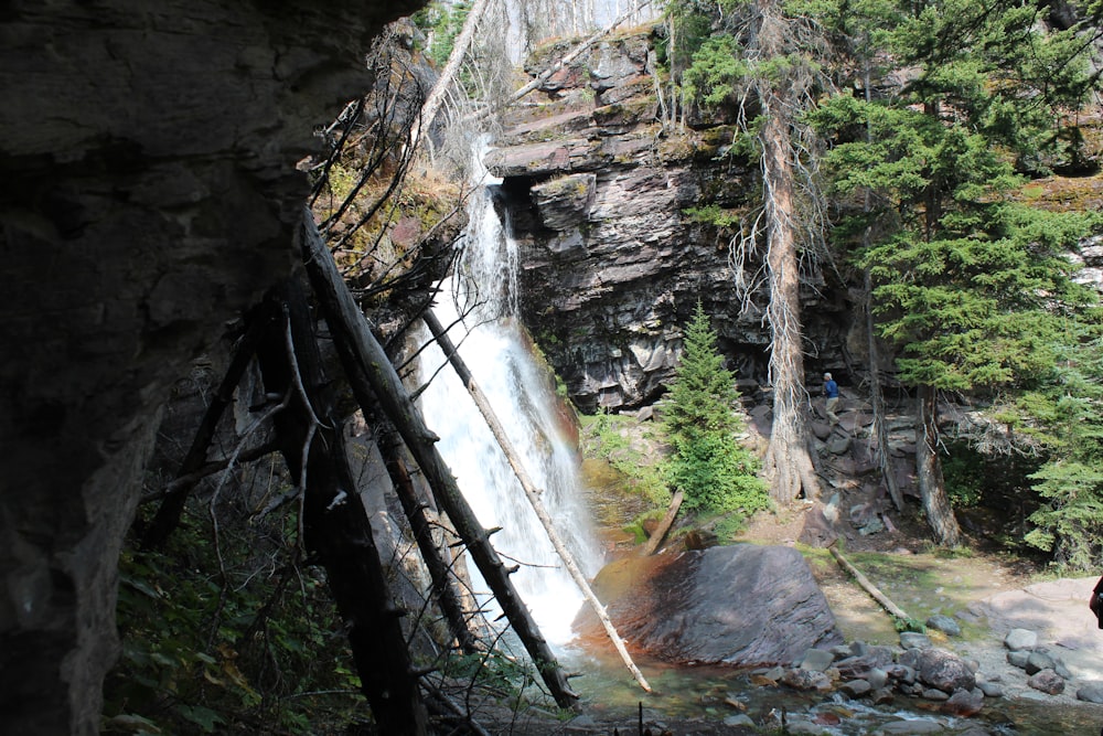 a man is standing at the base of a waterfall