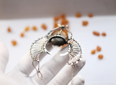 Artisan hands delicately setting a gemstone into a modern, geometric pendant.